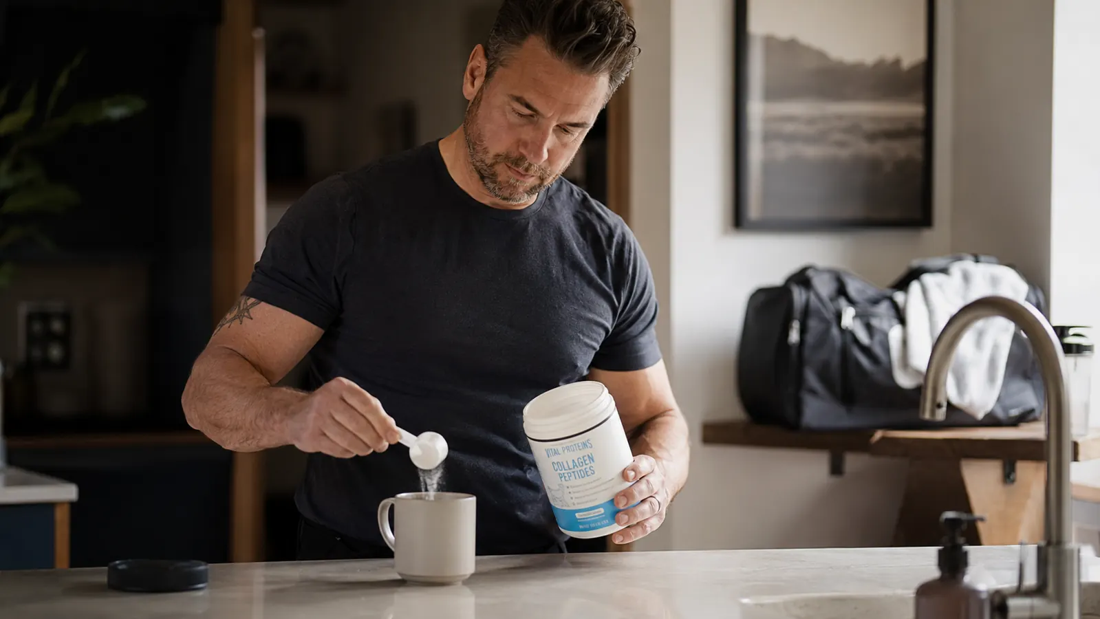 Man in his 40s stirring a scoop of collagen peptides into black coffee in a kitchen before an early workout