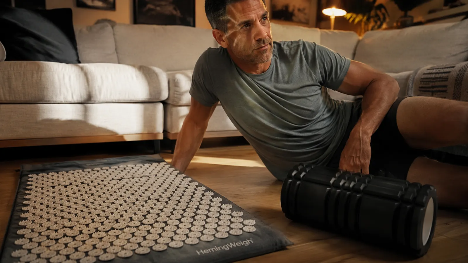 An acupressure mat and a foam roller laid side by side on a living room floor
