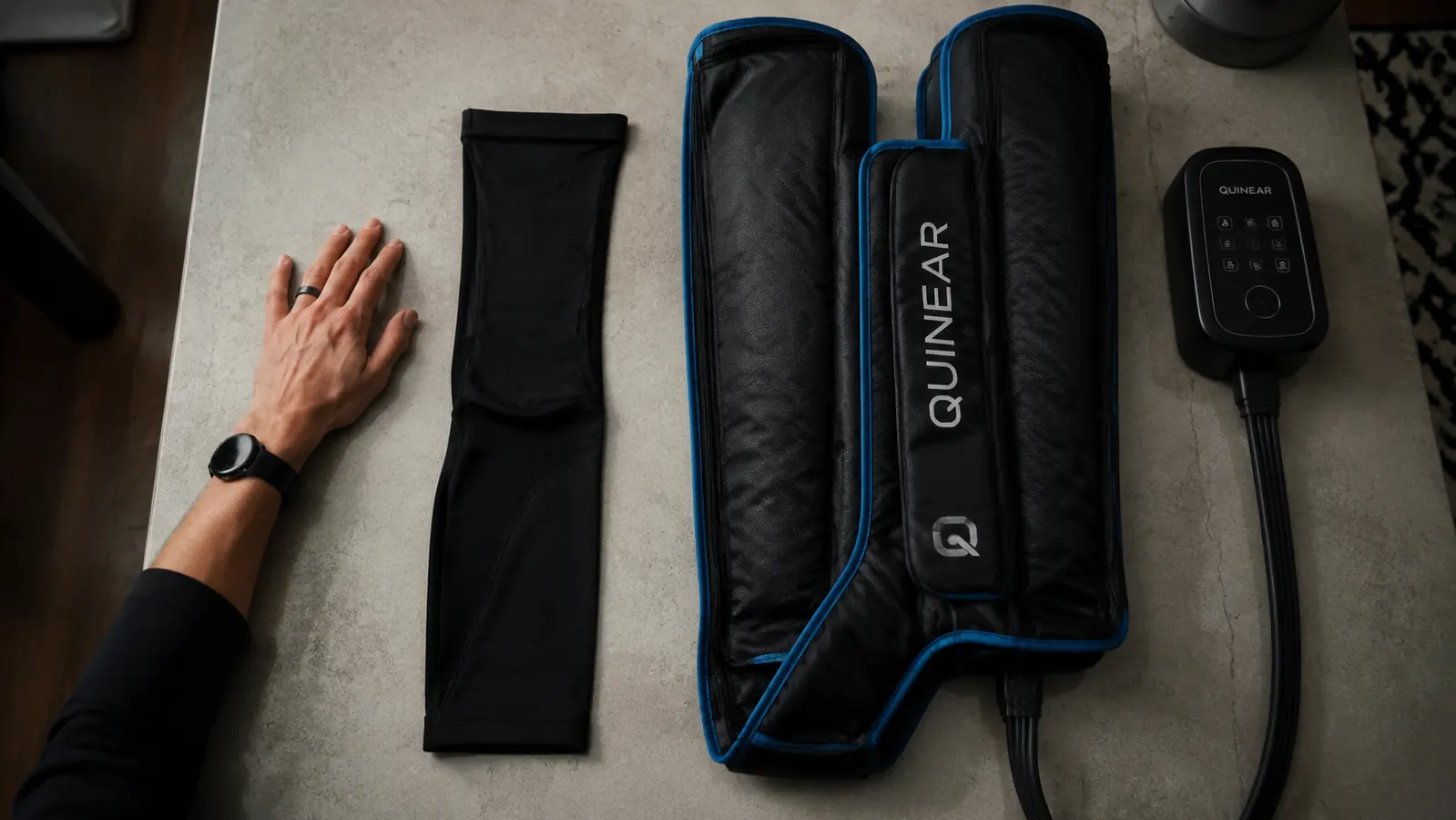 Hand comparing a small compression sleeve on a table next to the bulkier QUINEAR boot and controller unit